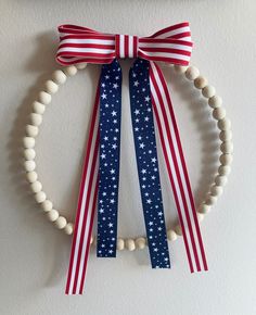 a red, white and blue bracelet with beads hanging from it's side on a wall