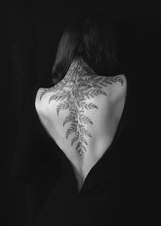 the back of a woman's neck with leaves on it