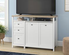 a flat screen tv sitting on top of a white cabinet