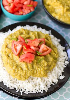 two black plates with rice, tomatoes and green sauce on them next to bowls of vegetables