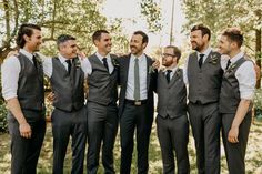 a group of men standing next to each other in front of some trees and grass