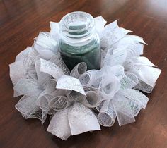 a mason jar is sitting on top of a white mesh wreath