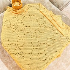 a yellow crocheted tablecloth with a wooden bowl on it sitting on a couch