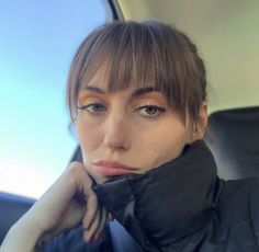 a woman sitting in the back seat of a car with her hand on her chin