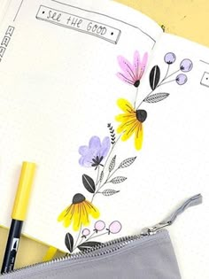 an open notebook with flowers painted on it and a pencil in the pocket next to it