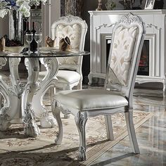 a white dining room table with two chairs and a vase on top of the table