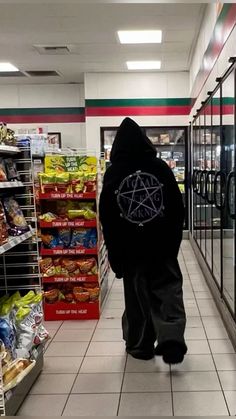 a person in a black hoodie walking down a store aisle with food on the shelves