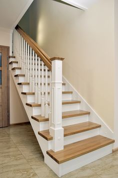 a staircase with white railing and wood handrails