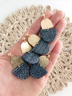 the earrings are made from wood and have geometric designs on them, with gold accents