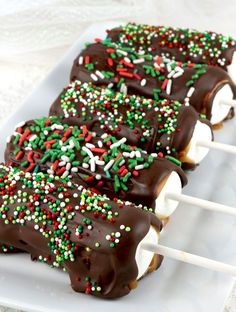 chocolate covered marshmallow pops on a plate with sprinkles and white sticks