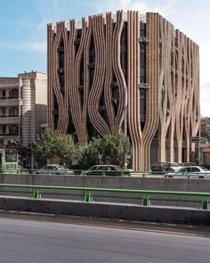 an unusual building in the middle of a street with cars parked on it's sides