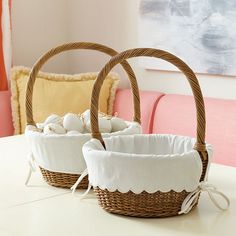 two wicker baskets sitting on top of a white table next to each other with eggs in them