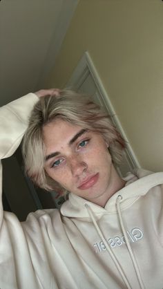 a man with blonde hair wearing a white hoodie