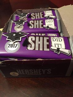 two chocolate bars with graduation decorations on them sitting in a cardboard box that says she did it