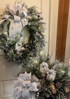 two wreaths with bows and pine cones are hanging on the front door, decorated for christmas