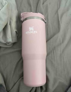 a pink tumbler sitting on top of a bed