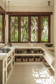 a kitchen filled with lots of white counter top space next to a sink and window