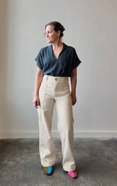 a woman standing in front of a window wearing white pants and a black top with colorful socks