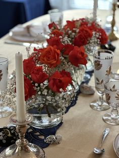 the table is set with red roses and silver candlesticks for an elegant centerpiece