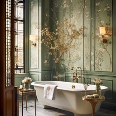 an ornate bathroom with green walls and white bathtub in the center is decorated with flowers