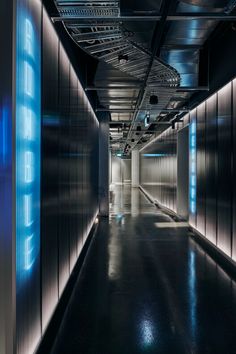 an empty hallway with blue lights on the walls and black flooring in front of it