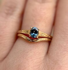 a woman's hand with a gold ring and a blue topazte stone