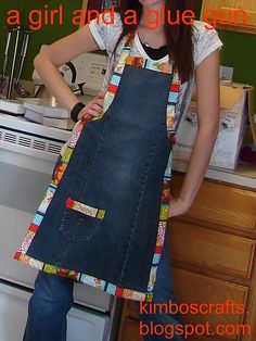 a woman standing in front of an oven holding a blue apron