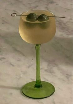 two olives in a wine glass sitting on a table