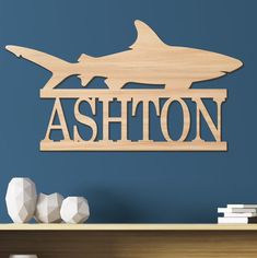 a wooden sign that says ashton on it in front of a shelf with books and vases