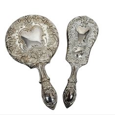 two silver spoons with ornate designs on the sides and one has a heart shaped handle