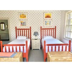 two twin beds in a room with wallpaper and pictures on the walls behind them