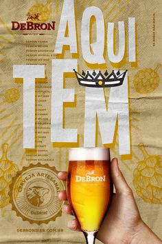 a person holding a beer glass in front of a poster with the words aquau tem on it