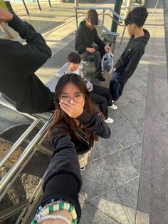 a group of people sitting next to each other on a metal bench in front of a building