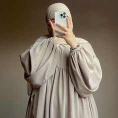 a woman taking a photo with her cell phone wearing a hijab and veil