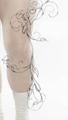 a woman's legs with an artistic tattoo on them and white stockings over her