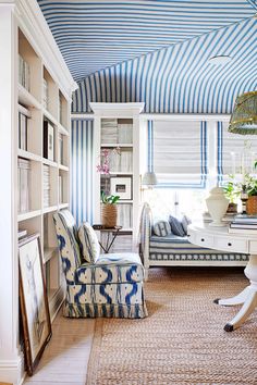 a blue and white striped ceiling in a living room with chairs, bookshelves and a desk