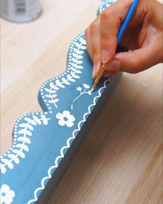 a person writing on a piece of paper with a blue and white flowered design