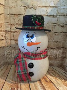 a snowman with a hat and scarf on it's head is standing in front of a brick wall