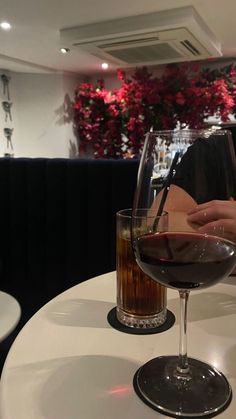 a person sitting at a table with a glass of wine in front of them on the table