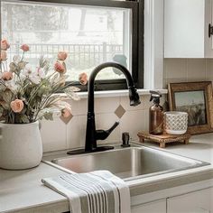 a kitchen sink sitting under a window next to a potted plant on top of a counter