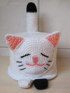 a crocheted cat is sitting next to a wine bottle