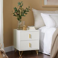 a bedroom with a bed, nightstand and plant on the end table in front of it