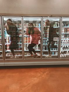 two people are reflected in the glass doors of a refrigerated beverage cooler