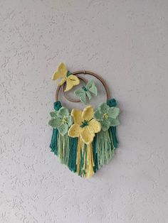 a circular wall hanging with flowers and leaves on the outside, attached to a white wall