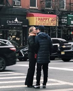 two people standing in the street kissing each other