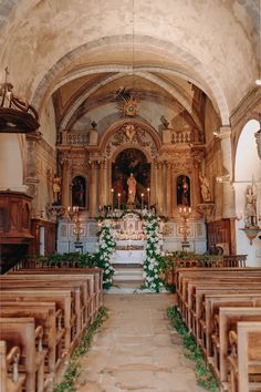 the interior of an old church with pews and flowers on the alter, surrounded by greenery