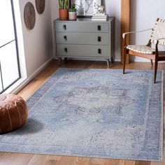 a living room area with a rug, chair and plant on the side table in front of a window