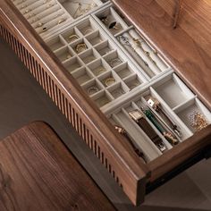 an open drawer filled with jewelry on top of a wooden table