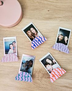 four polaroid photos are placed on a wooden table next to a pink alarm clock