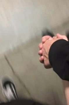 two people holding hands in front of a wall